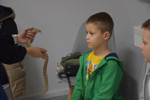 Zdjęcie przedstawia chłopca trzymającego węża